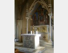 Interno di una chiesa con piccolo altare in marmo su pedana rialzata, sotto archi gotici sorretti da colonne. Sul fondo si vedono un grande affresco religioso nella nicchia absidale e un pannello decorato a motivi geometrici lungo il presbiterio.