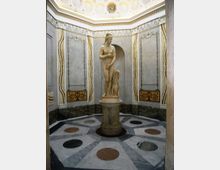 Interno di una sala ottagonale in stile classico, con pareti decorate da pannelli e cornici in stucco e un soffitto a cassettoni. Al centro si trova una statua su piedistallo su un pavimento in marmo geometrico con inserti circolari.