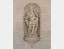 Statua in pietra collocata in una nicchia ad arco su una facciata in muratura chiara, con basamento sporgente e iscrizione “LOTARIO TERTIO”. La figura scolpita indossa un mantello e una tunica e tiene un oggetto nella mano, in stile monumentale.