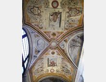Volta interna di una chiesa o cappella con archi incrociati, interamente decorata con affreschi e stucchi ornamentali. Al centro e nei riquadri compaiono figure e medaglioni dipinti, con una grande finestra ad arco sul lato sinistro.