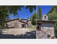 Complesso rurale in pietra con edifici a tetto in coppi e piccola struttura campanaria, affacciato su un cortile in ghiaia. Intorno si vedono alberi alti e vegetazione rigogliosa sotto un cielo sereno.