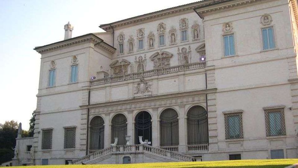 Facciata di una villa o palazzo storico in stile rinascimentale, con decorazioni a rilievo, finestre simmetriche e loggia ad archi al piano terra. Davanti si vede una scalinata con balaustra che conduce all’ingresso e un ampio prato verde in primo piano.