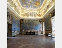 Ampia sala storica con pareti interamente affrescate con grandi mappe geografiche e decorazioni cartografiche, e un grande planisfero ovale sulla parete di fondo. Il soffitto a volta è riccamente dipinto con scene celesti e cornici ornamentali, con pavimento in cotto e file di sedie lungo un lato.