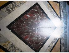 Pavimento interno in marmo con motivo geometrico a rombo, composto da lastre policrome venate e bordature chiare e scure. Al centro è visibile un riquadro di marmo rosso maculato, incorniciato da fasce di marmo bianco e nero.