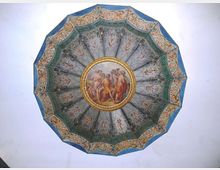 Affresco su soffitto circolare decorato con un motivo a raggiera e un medaglione centrale con figure classiche, incorniciato da bordure ornate in verde, oro e azzurro. Sfondo chiaro che evidenzia la struttura ottagonale della cornice esterna.