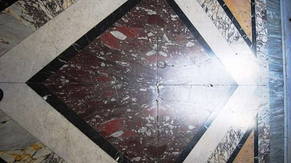 Pavimento interno in marmo con motivo geometrico a rombo, composto da lastre policrome venate e bordature chiare e scure. Al centro è visibile un riquadro di marmo rosso maculato, incorniciato da fasce di marmo bianco e nero.