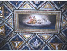 Soffitto interno riccamente affrescato con pannelli geometrici a rombi e triangoli, decorati con figure e motivi ornamentali. Al centro, un grande riquadro dipinto raffigura un carro trainato da cavalli, incorniciato da bordi dorati.