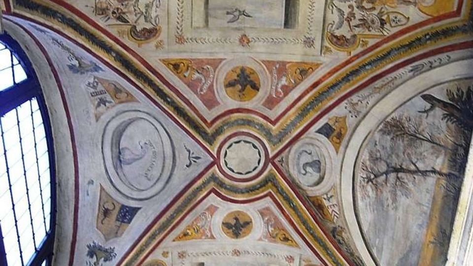 Volta interna di una chiesa o cappella con archi incrociati, interamente decorata con affreschi e stucchi ornamentali. Al centro e nei riquadri compaiono figure e medaglioni dipinti, con una grande finestra ad arco sul lato sinistro.